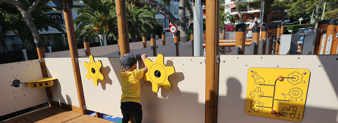 Boy playing on a ship's wheel on the platform of a multi-play structure 